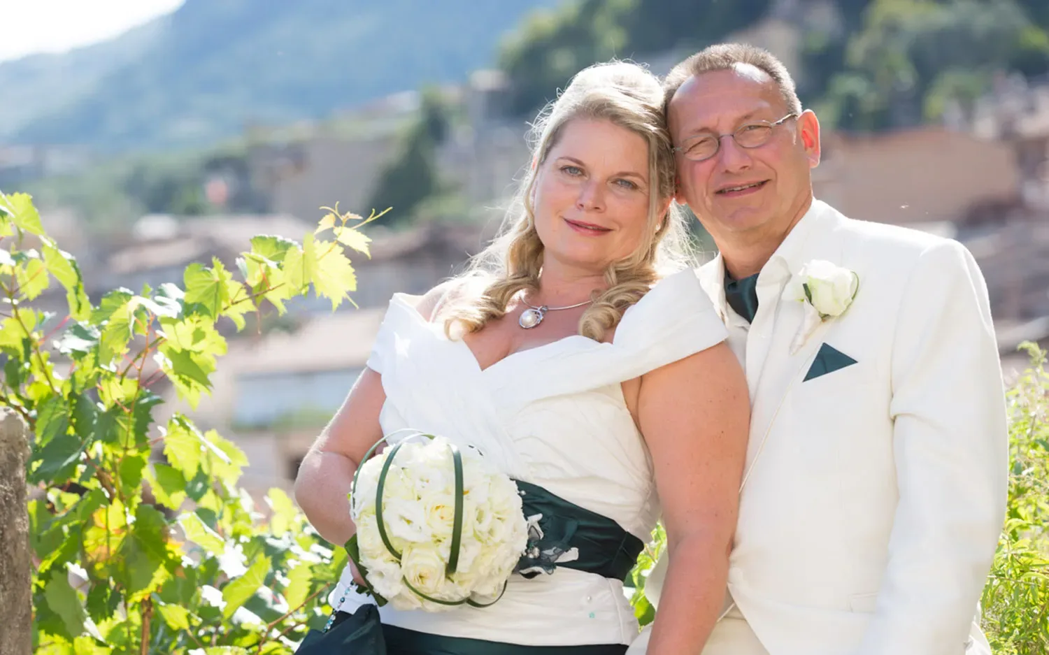 Lächelndes Brautpaar in eleganter Hochzeitskleidung im Freien