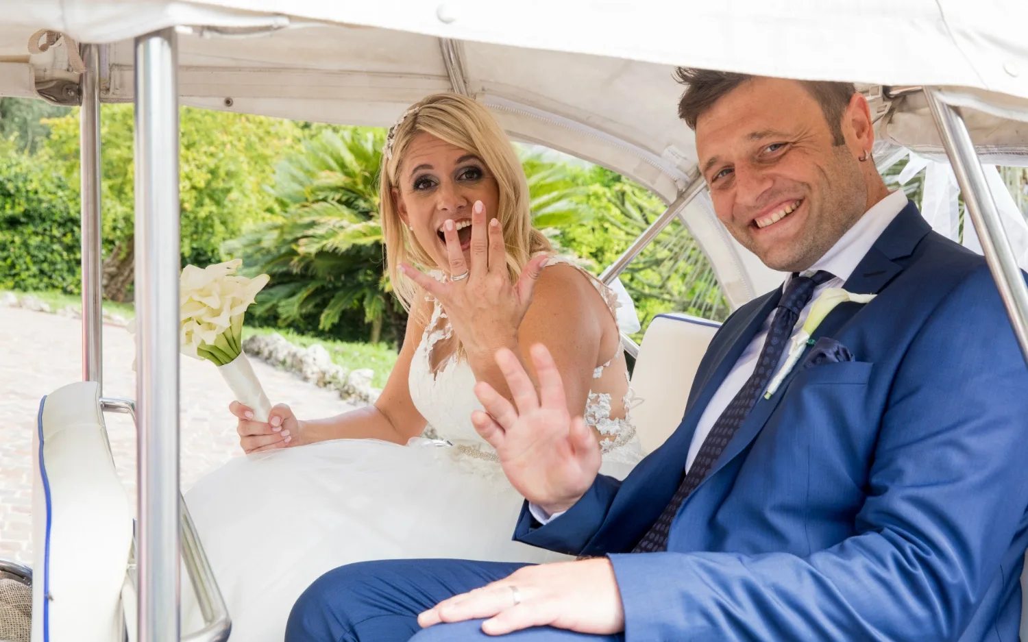 Lächelndes Brautpaar zeigt Eheringe im Hochzeitsauto