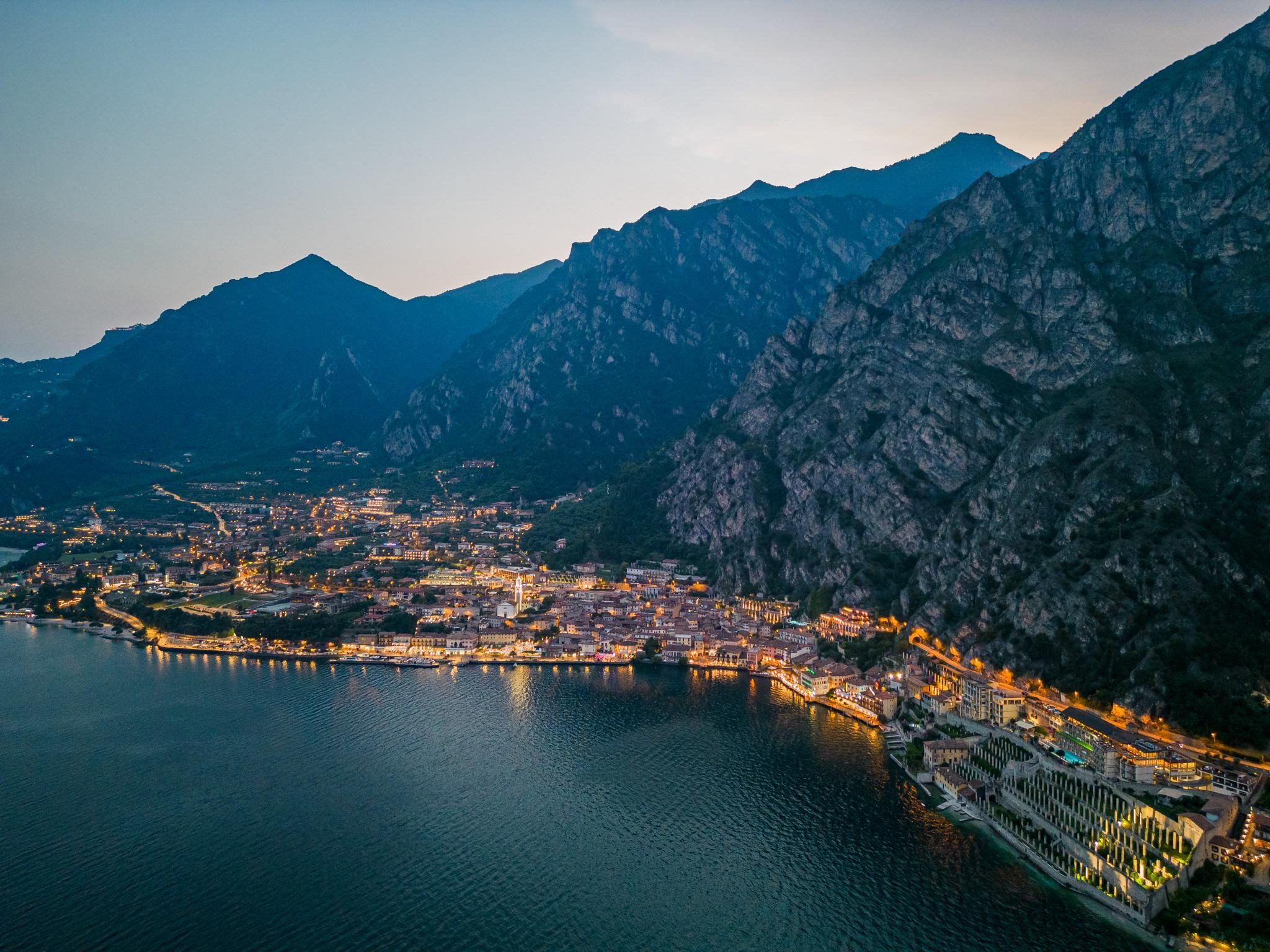 Night cityscape of lakeside town below tall mountain range